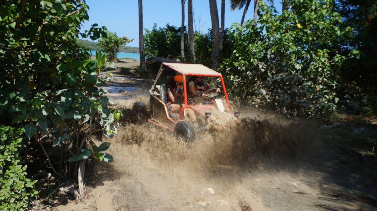 Buggy rojo recorriendo la ruta costera con el mar al fondo en Puerto Plata