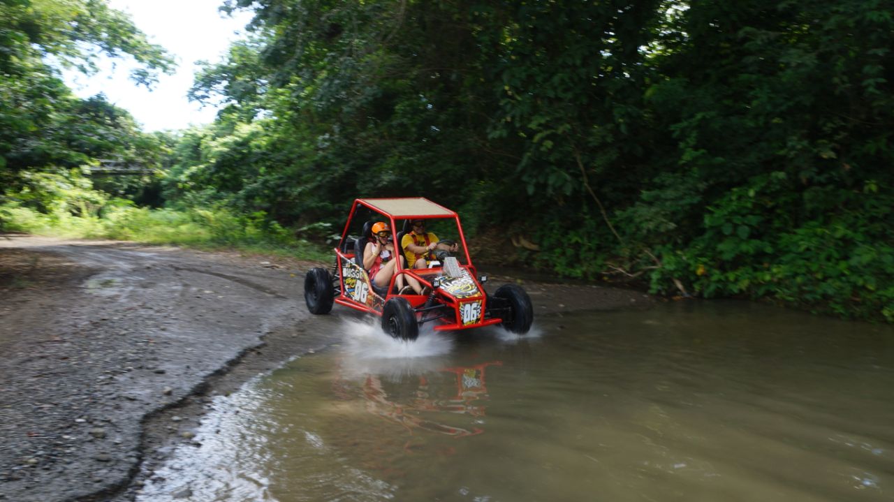 Buggy rojo entrando a charco en sendero de Maimón Puerto Plata