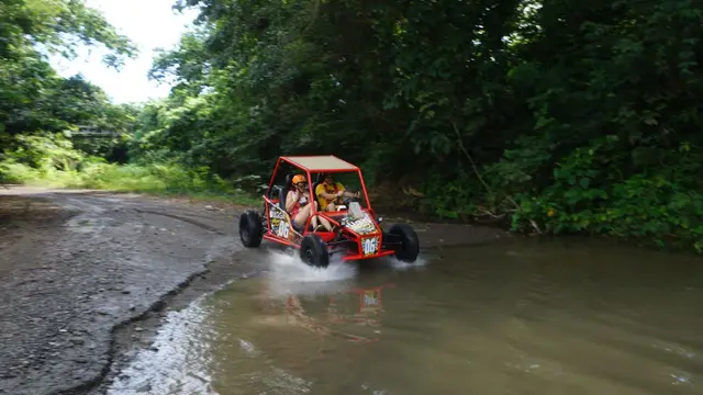 Buggy rojo entrando a un charco profundo en sendero off-road de Puerto Plata