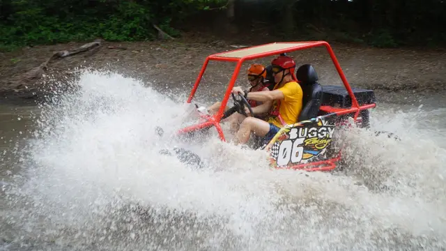 Buggy rojo provocando un gran salpique lateral en un riachuelo tropical
